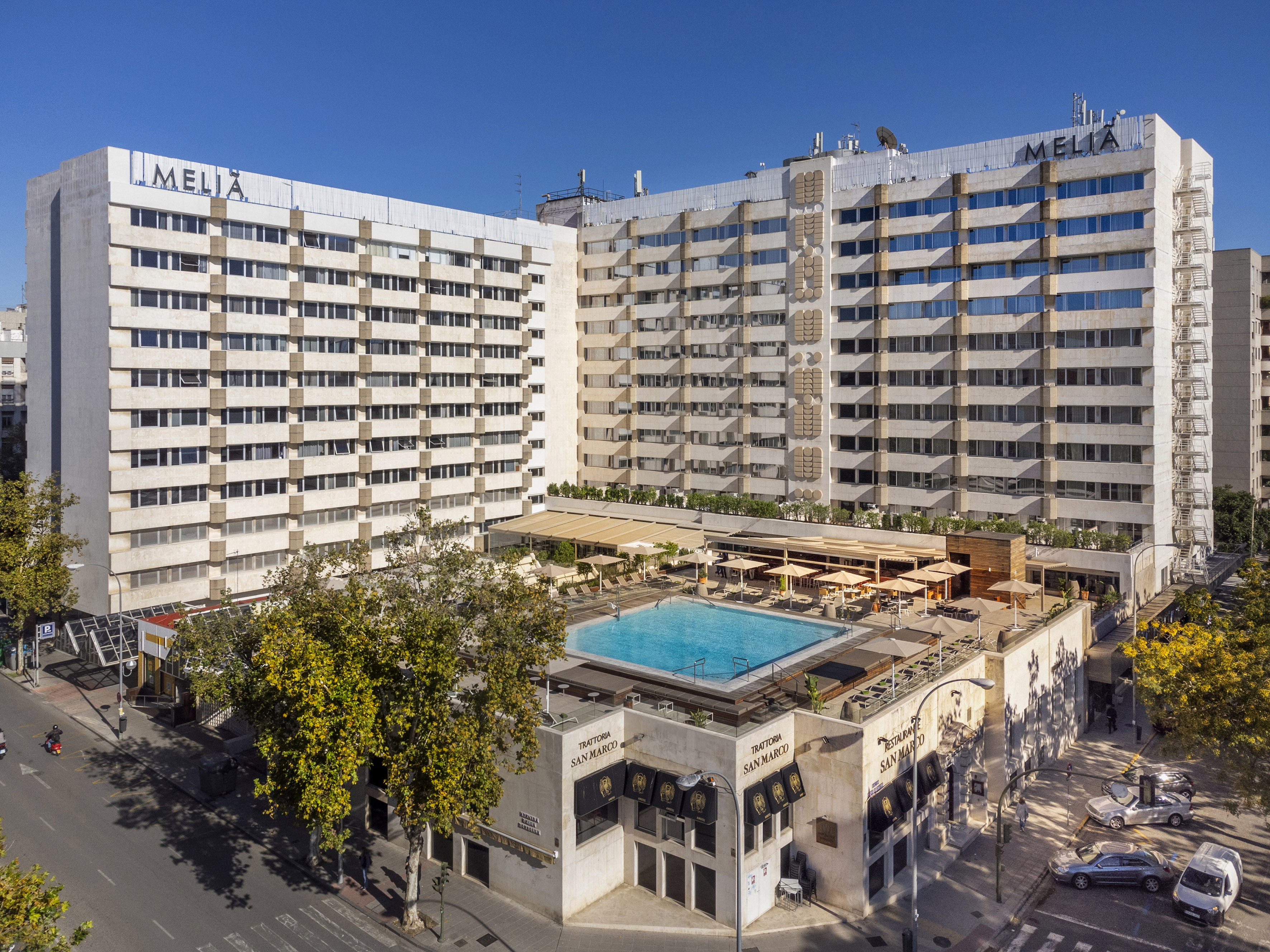 Melia hotel building with rooftop pool, sunny terrace, and street scene.