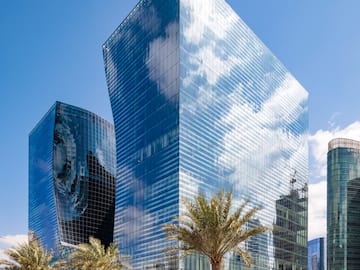a tall glass building with palm trees