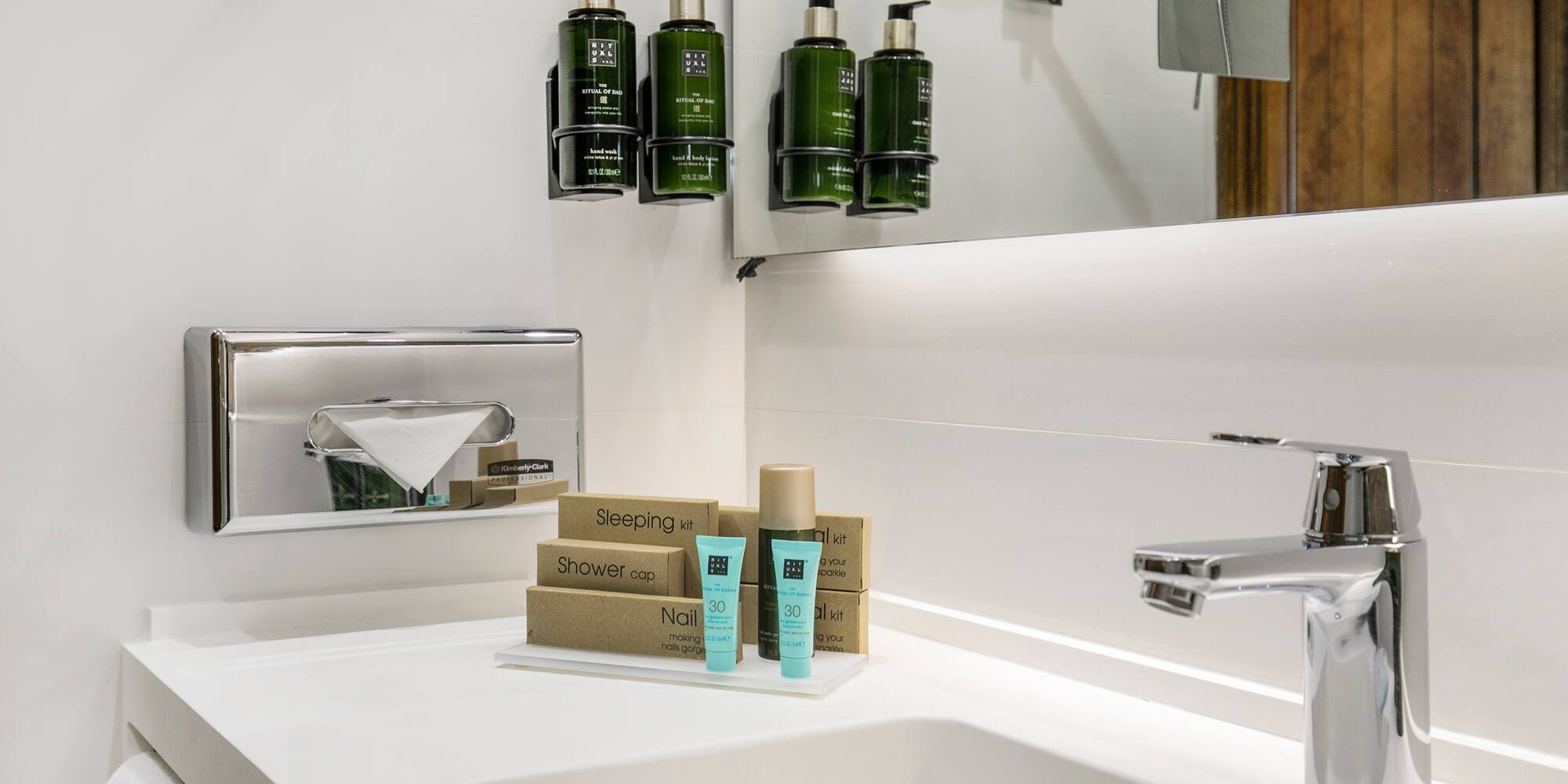 a bathroom sink with a mirror and a few bottles of shampoo