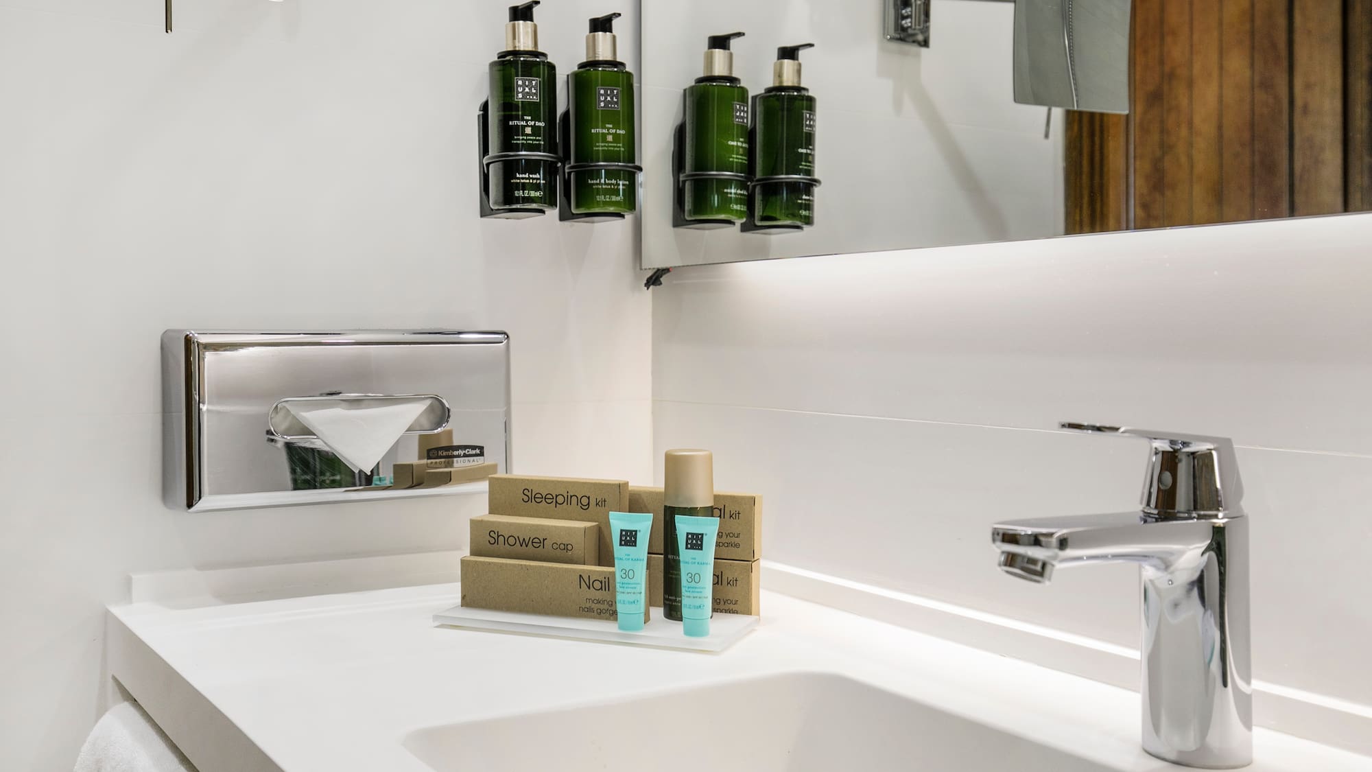 a bathroom sink with a mirror and a few bottles of shampoo