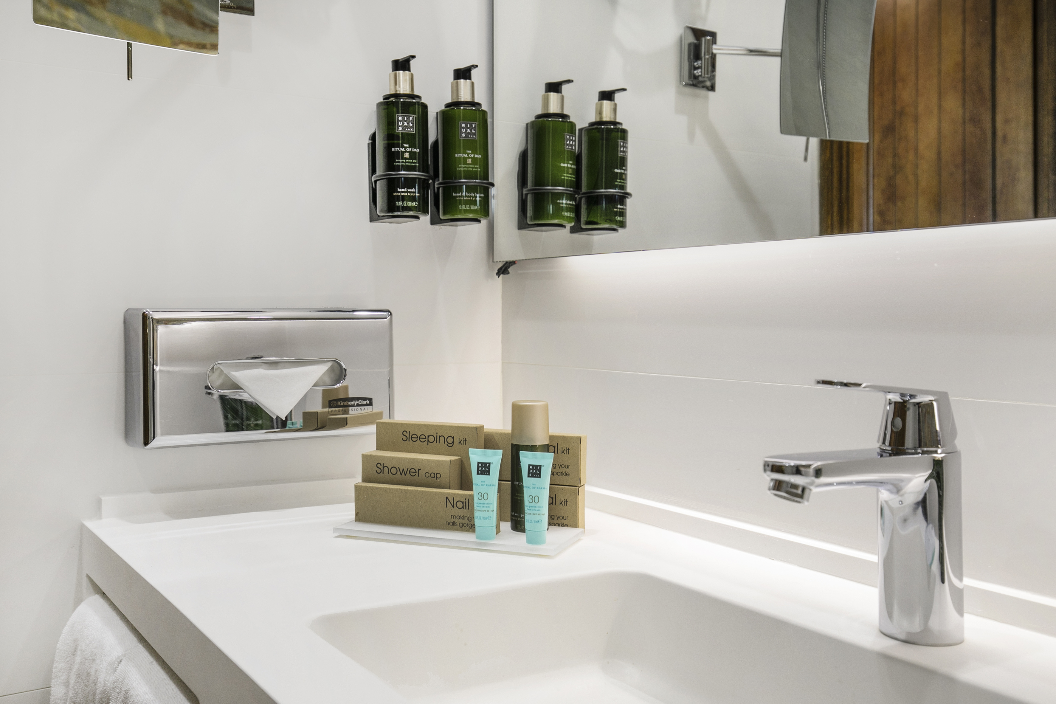 Hotel bathroom vanity with Rituals toiletries, chrome faucet, and guest amenity kits.