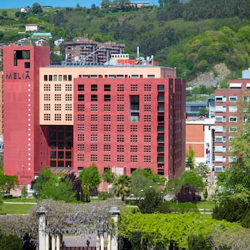 a large red building with trees and a hill in the background