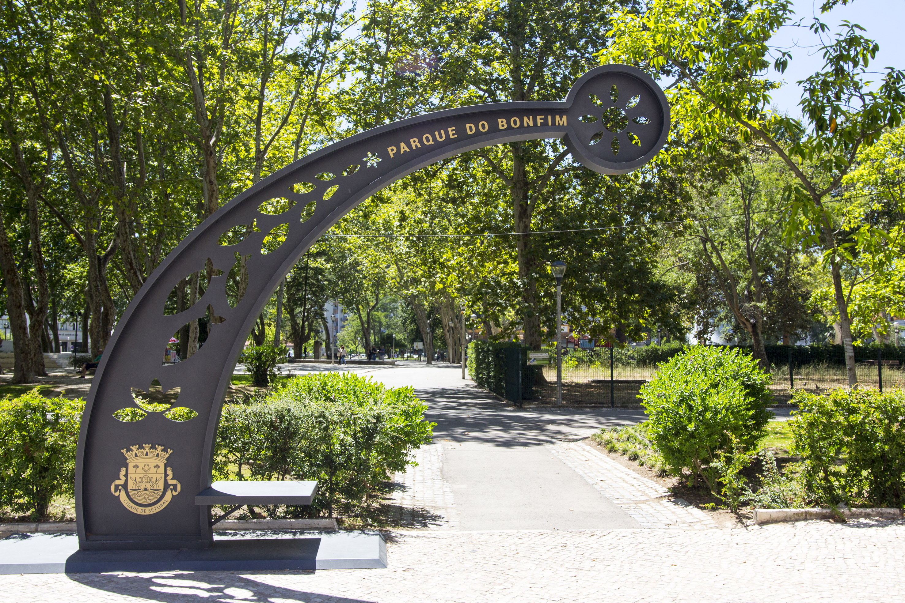 "Parque do Bonfim" entrance sign in Setúbal park, with green trees and pathway.