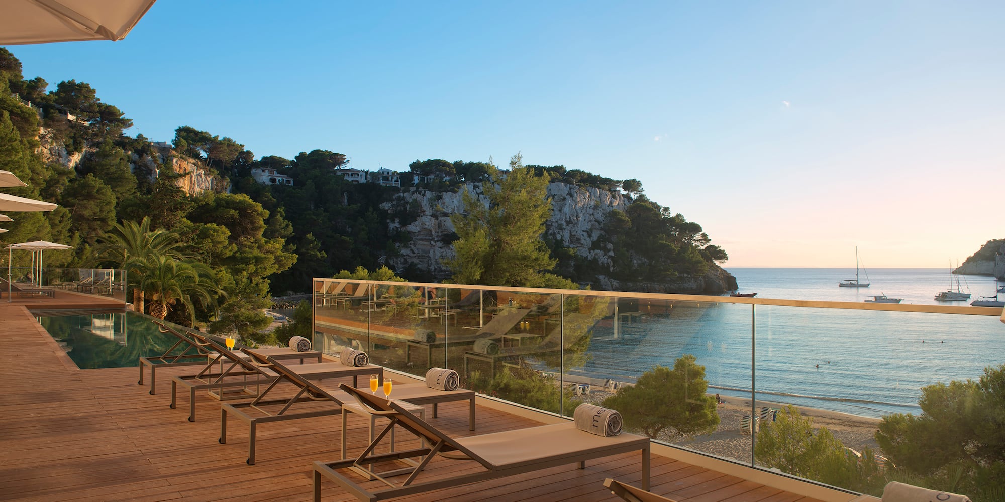 a deck with chairs and a glass railing overlooking a beach