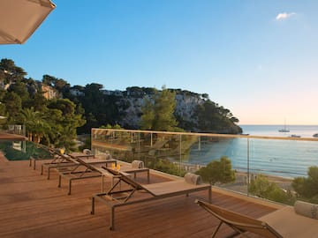a deck with chairs and a glass railing overlooking a beach