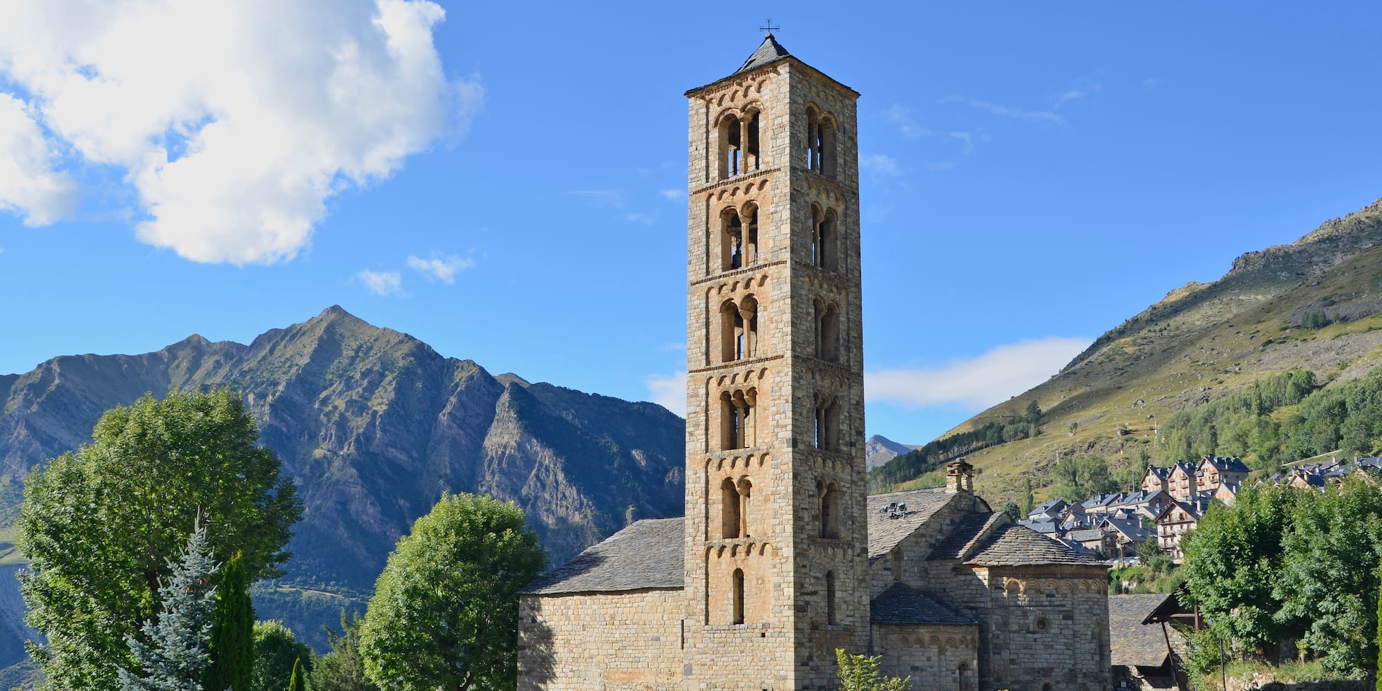 a stone building with a tower in front of a mountain