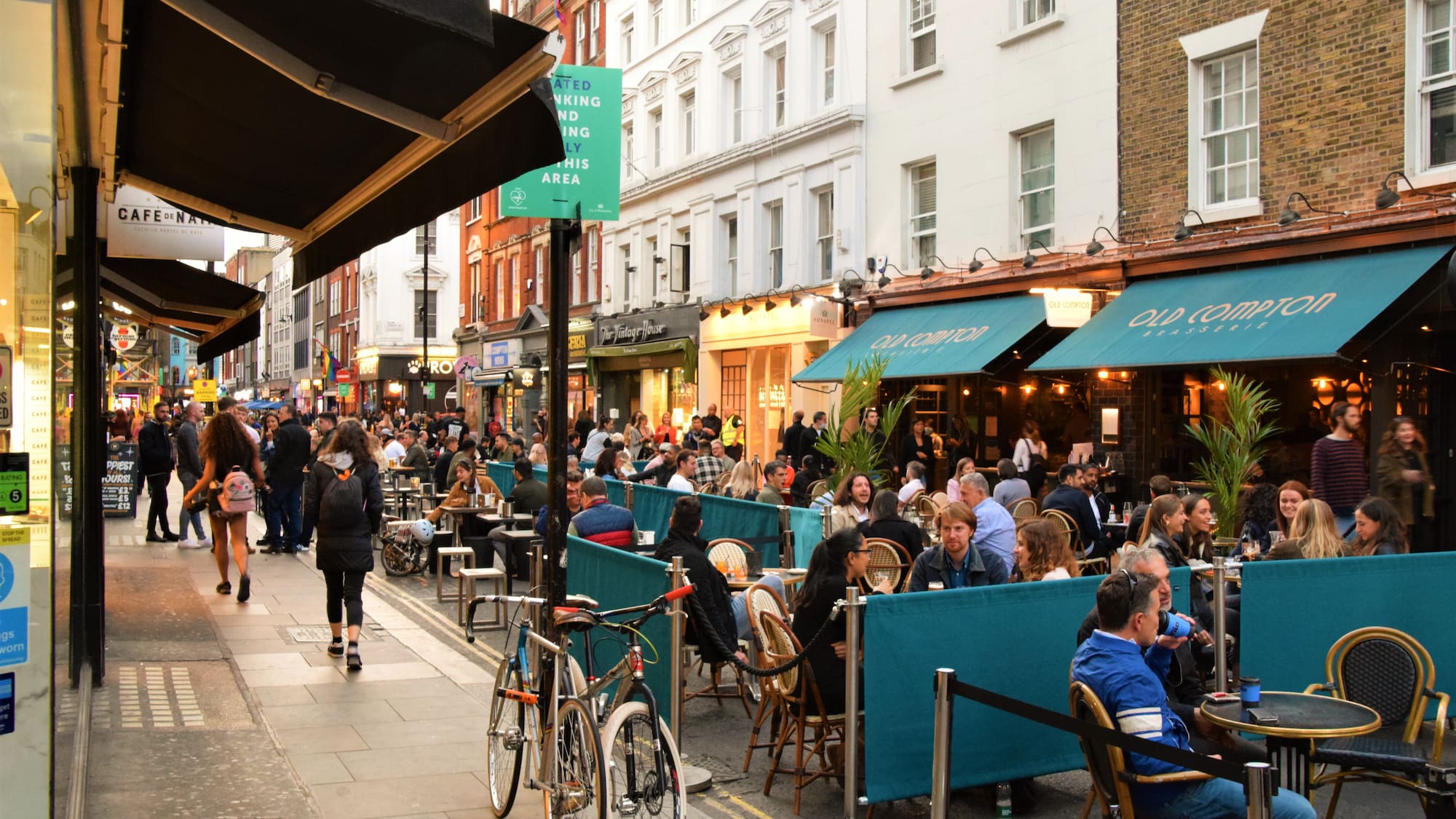A group of individuals gathered around tables outside a restaurant.