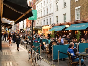 A group of individuals gathered around tables outside a restaurant.