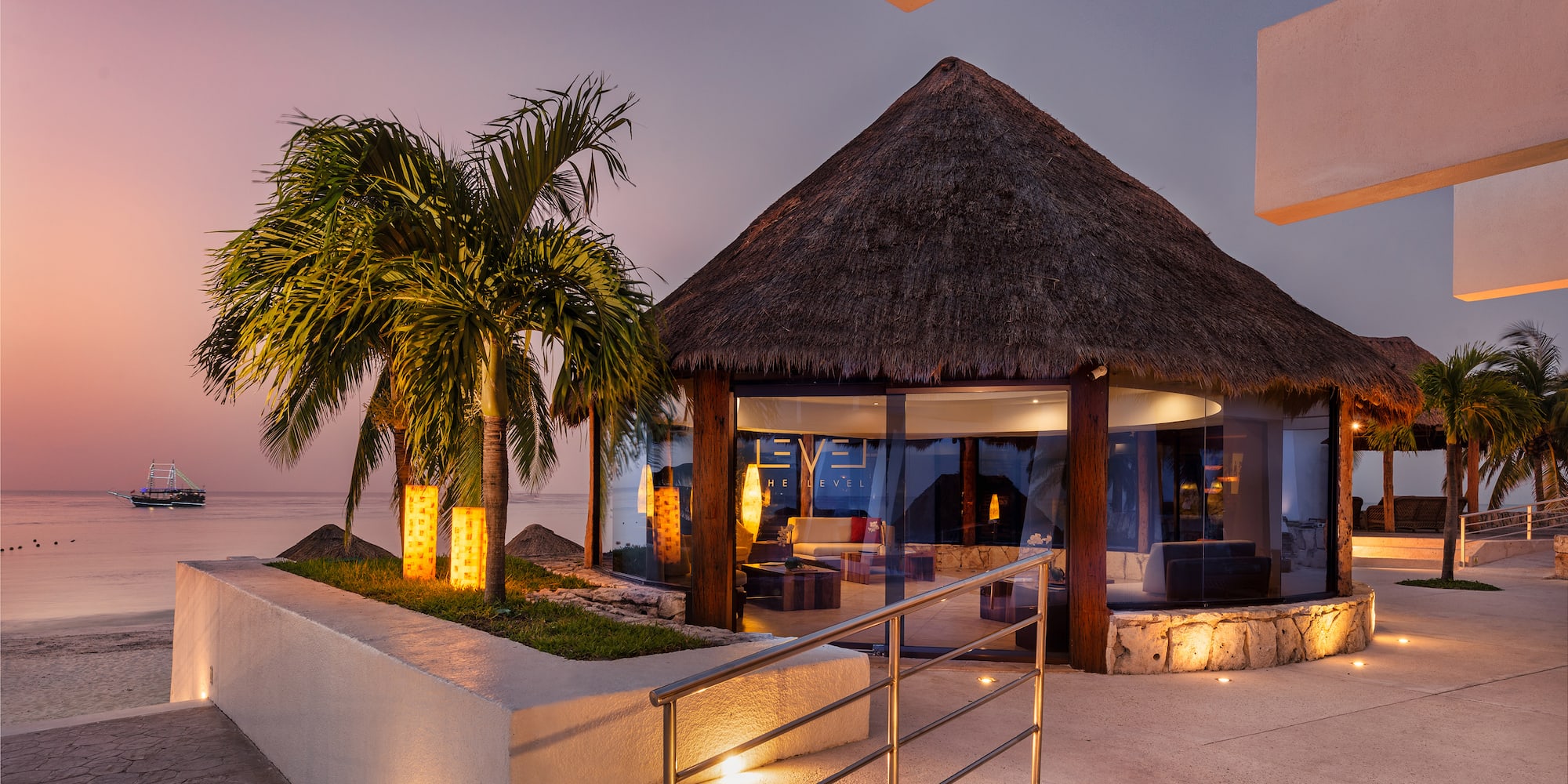 a building with a thatched roof and palm trees
