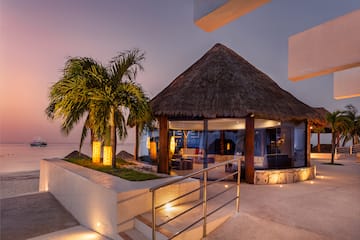 a building with a thatched roof and palm trees