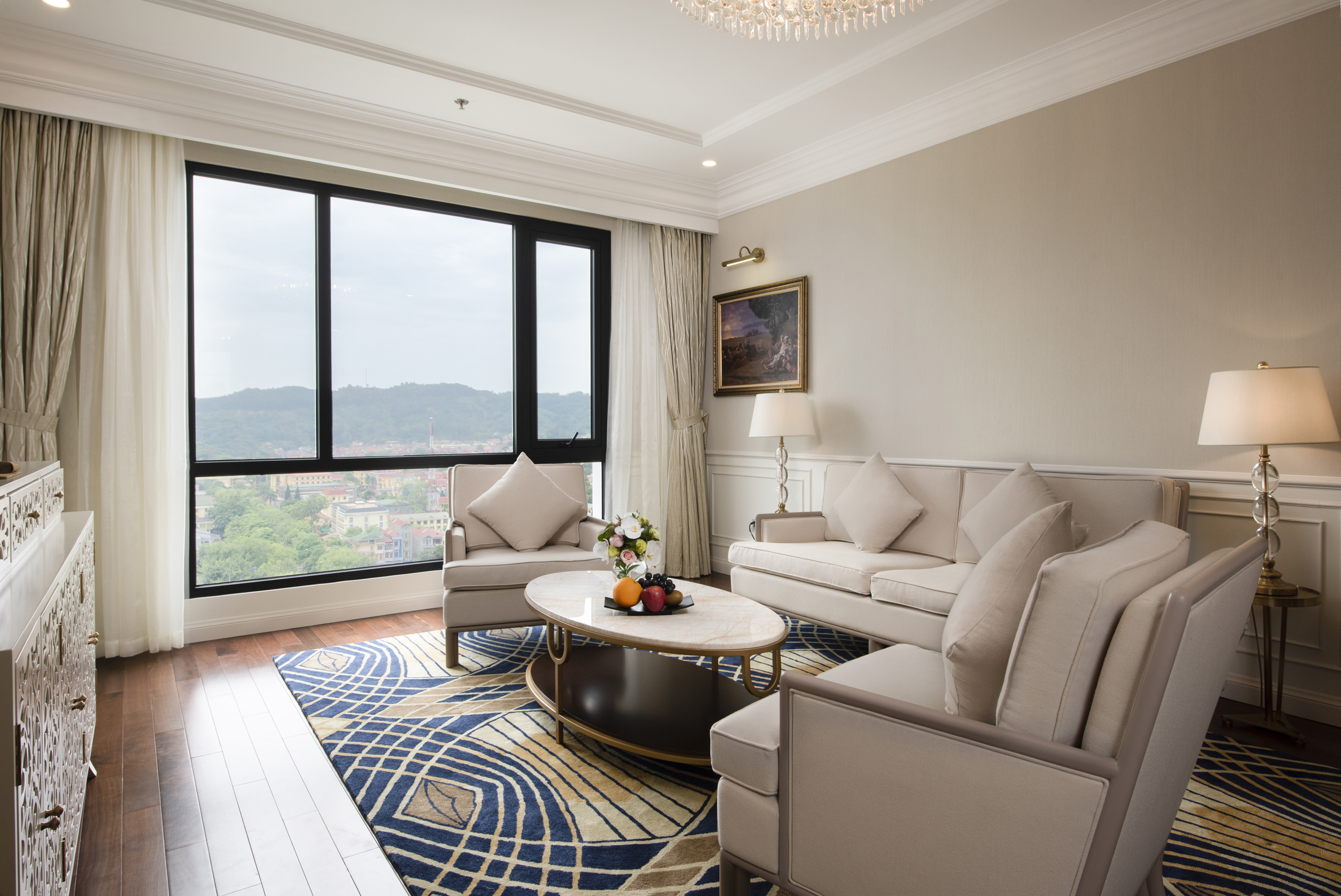 Luxury hotel living room with panoramic city view and modern decor.