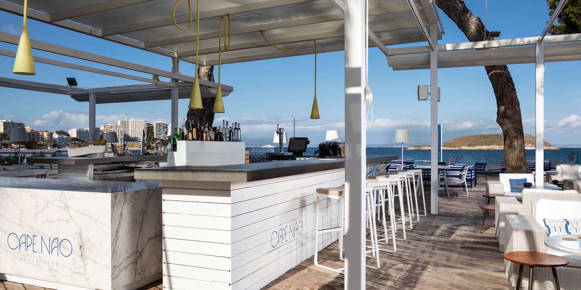 a white bar with chairs and tables on a deck