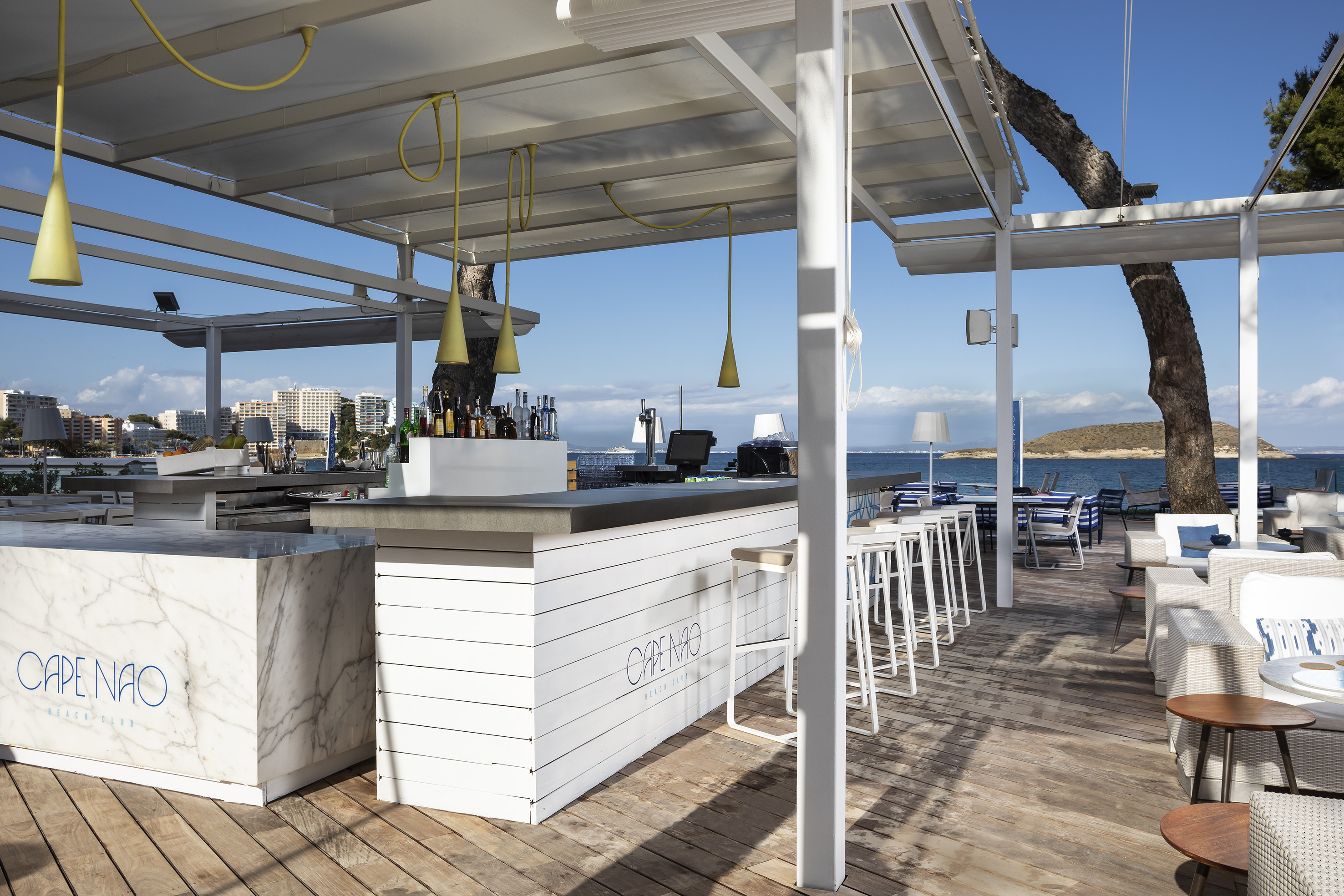 a white bar with chairs and tables on a deck