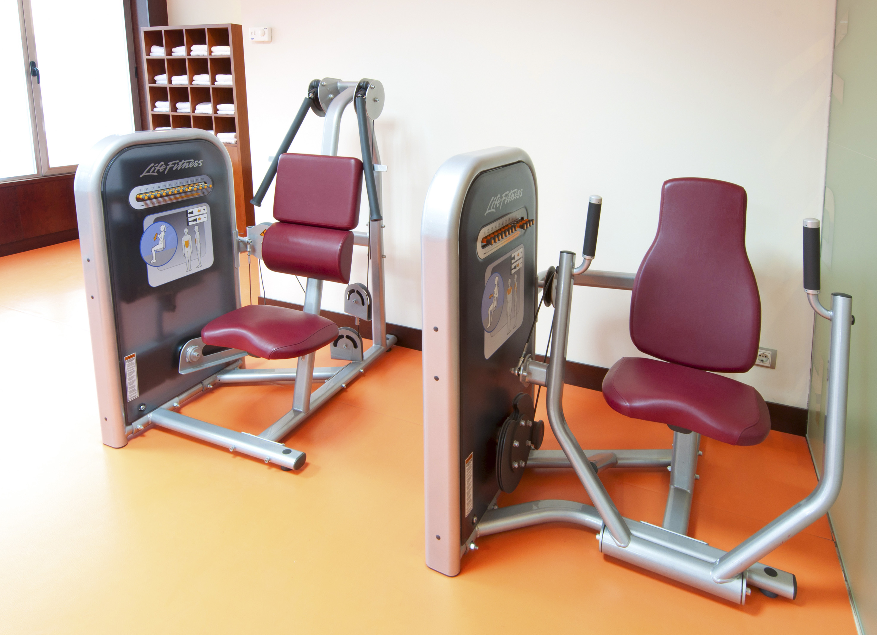 Life Fitness strength machines with red seats in a hotel gym or fitness center.