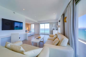 a living room with white furniture and a television