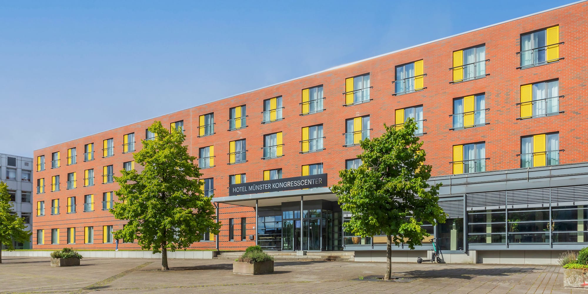 Hotel Münster Kongresscenter: Red brick building, yellow shutters, modern entrance.