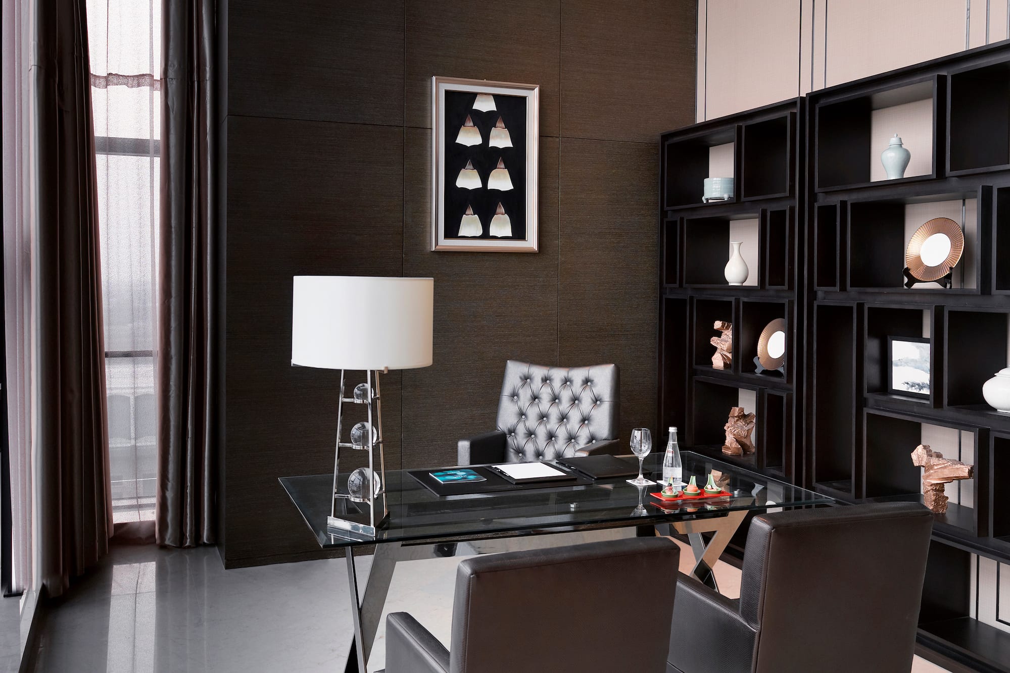 a desk with a lamp and a bookcase in a room