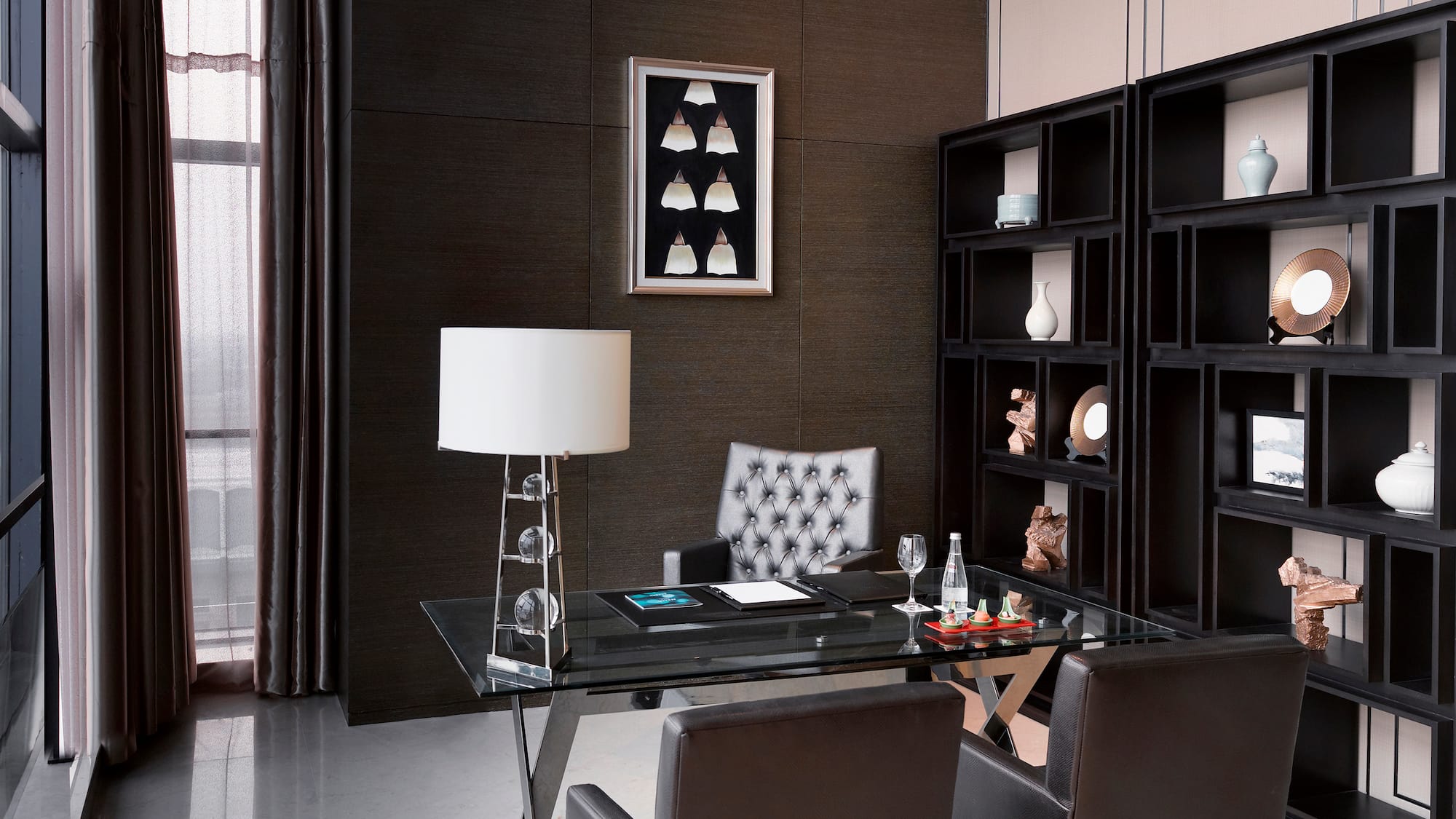 a desk with a lamp and a bookcase in a room