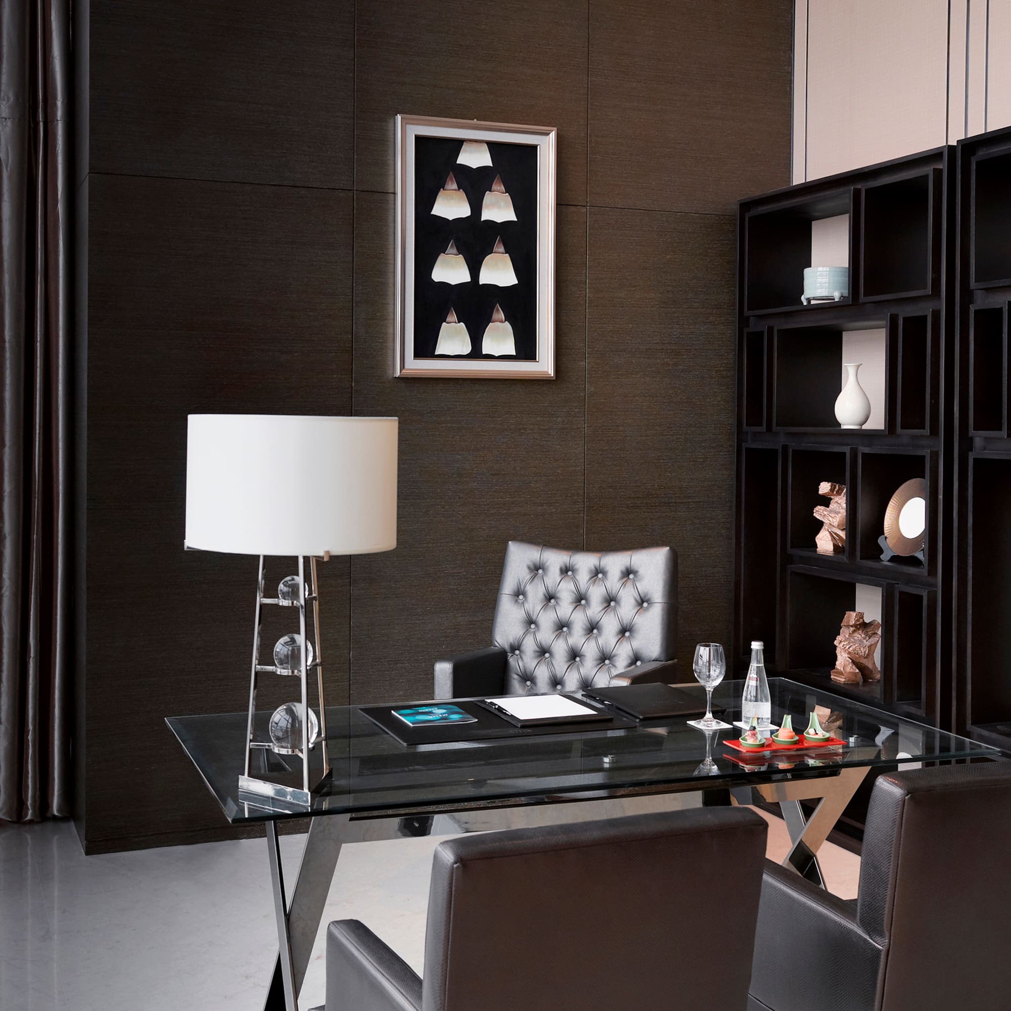 a desk with a lamp and a bookcase in a room