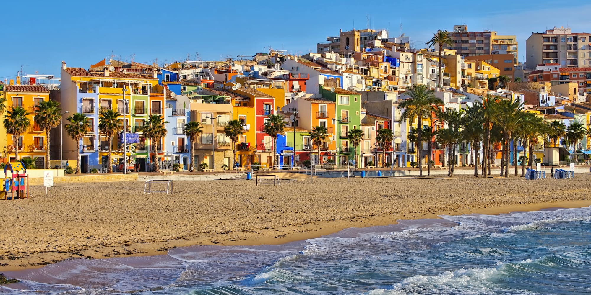 a beach with buildings and palm trees