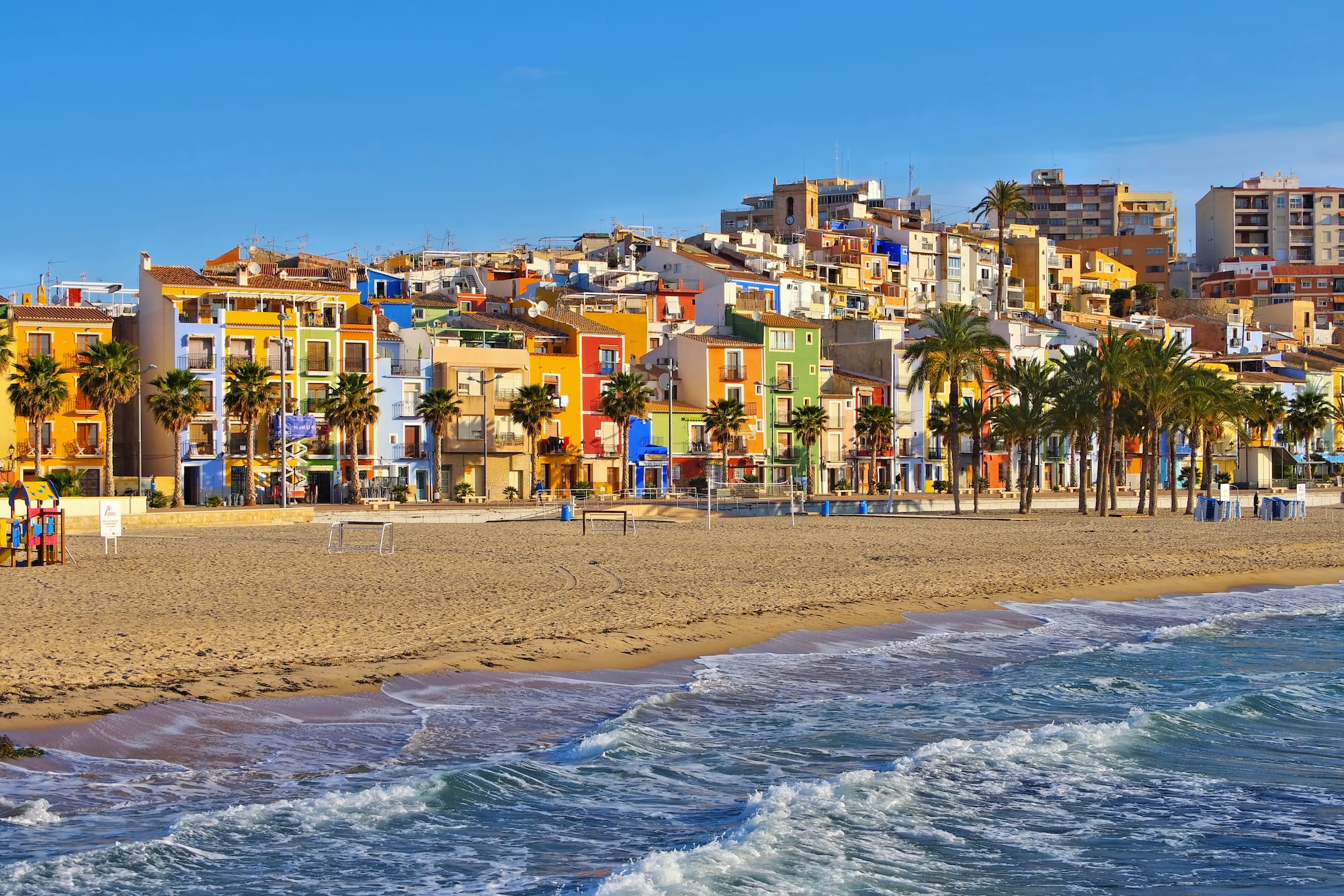 a beach with buildings and palm trees