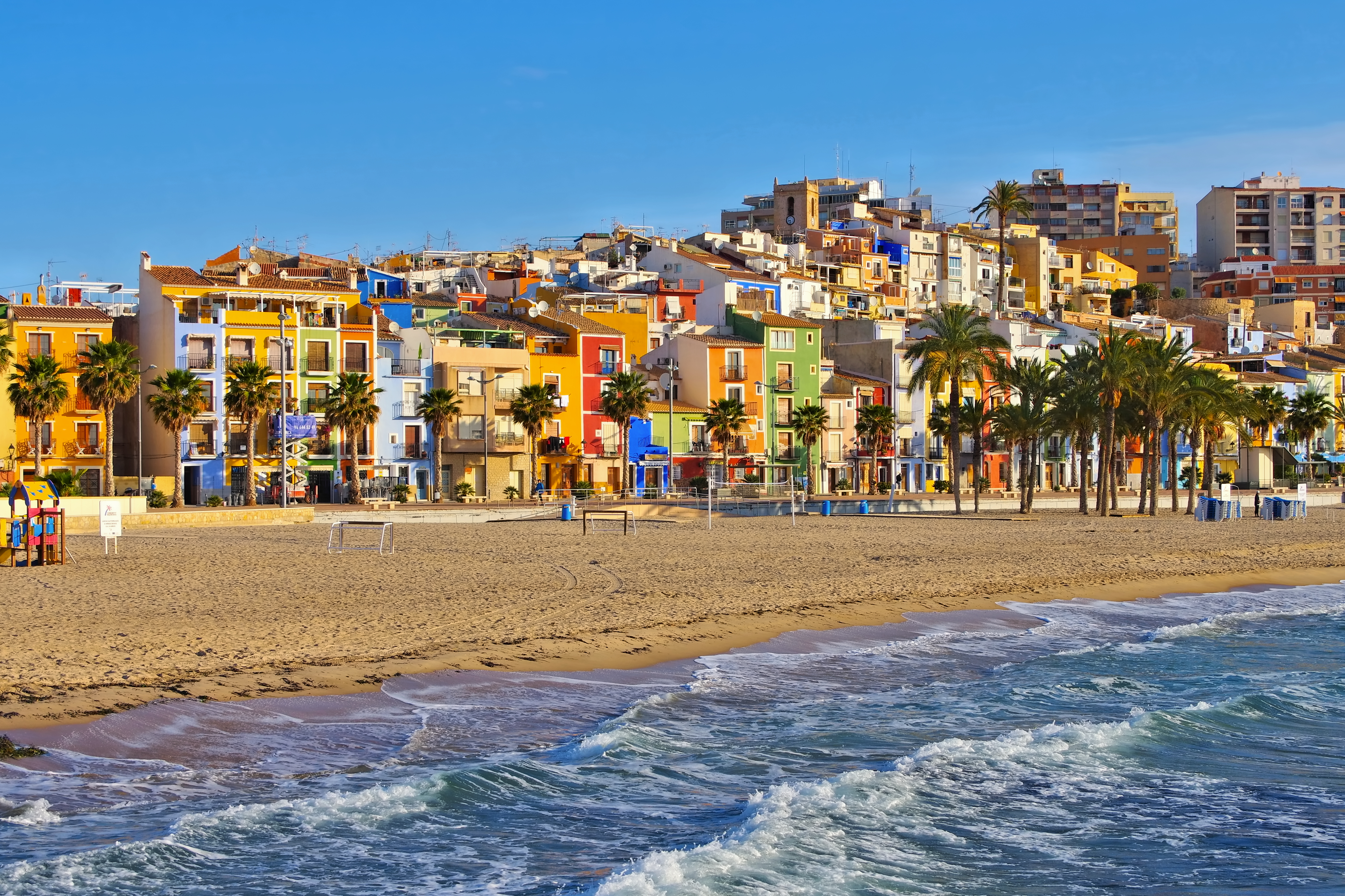 a beach with buildings and palm trees