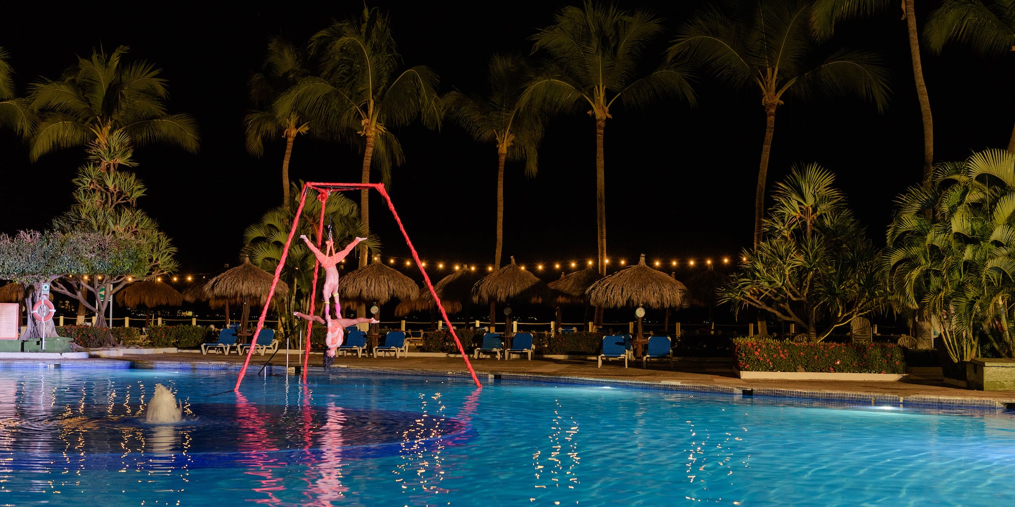 a person standing on a pole in a pool at night