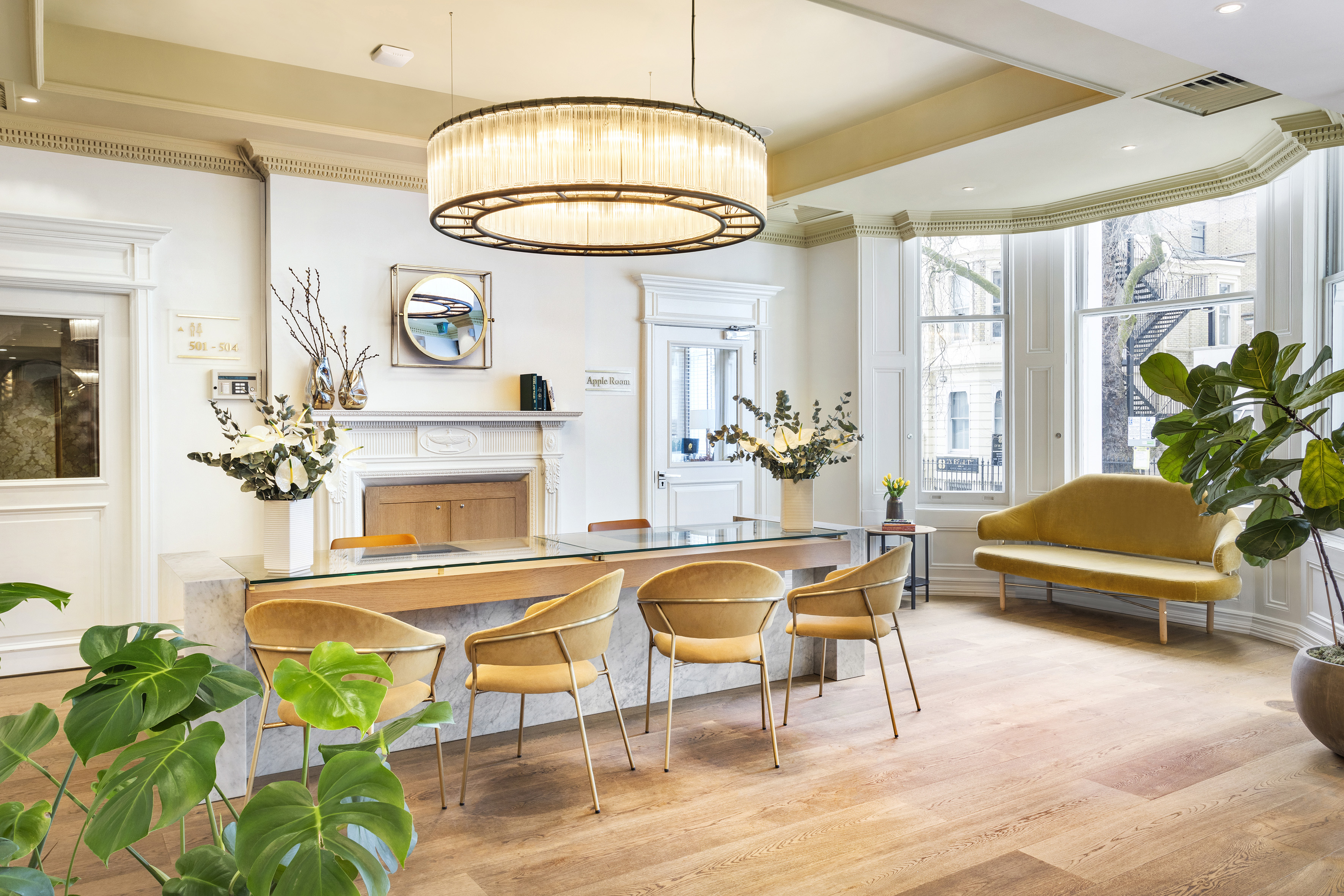 Modern hotel lobby with reception desk, gold chairs, and elegant lighting.
