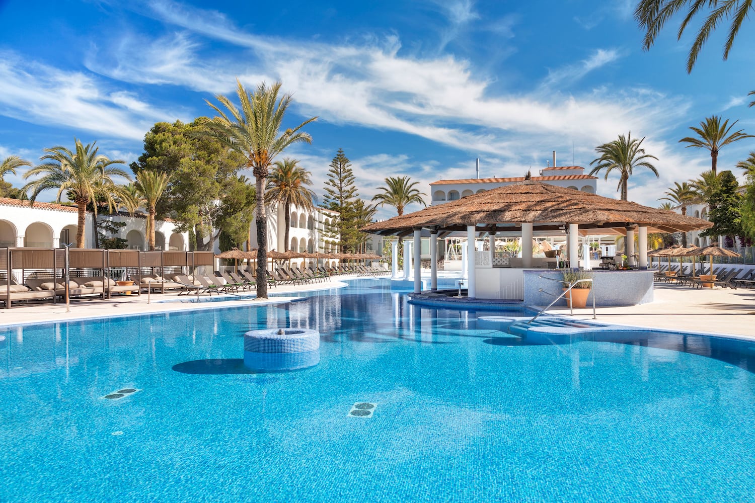 a pool with a bar and a building with palm trees