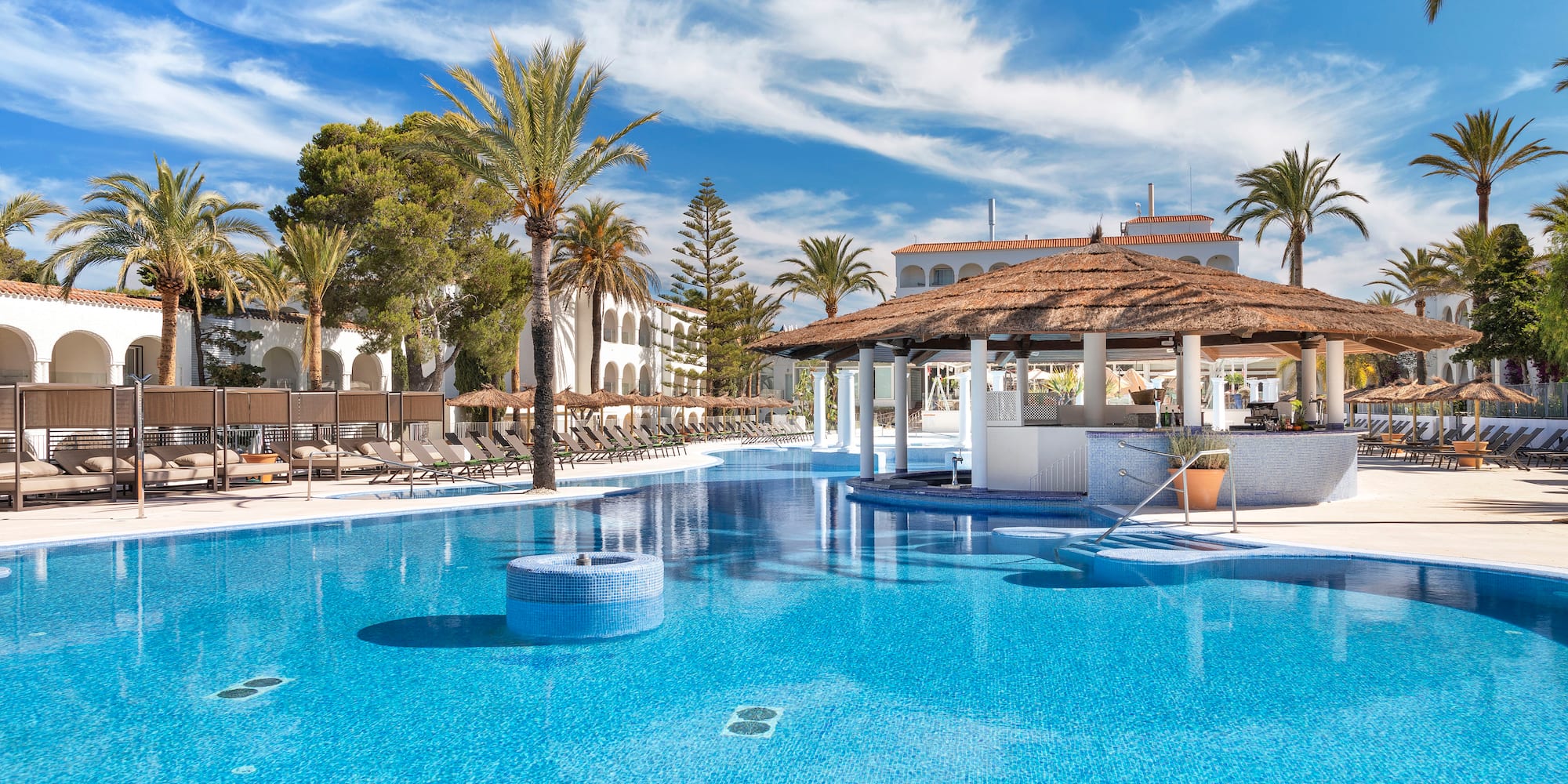a pool with a bar and a building with palm trees