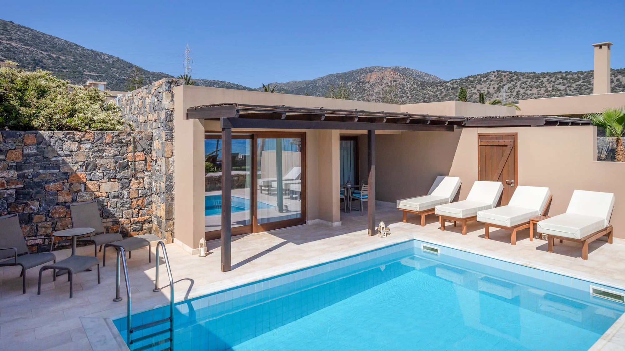 a swimming pool with chairs and a stone wall