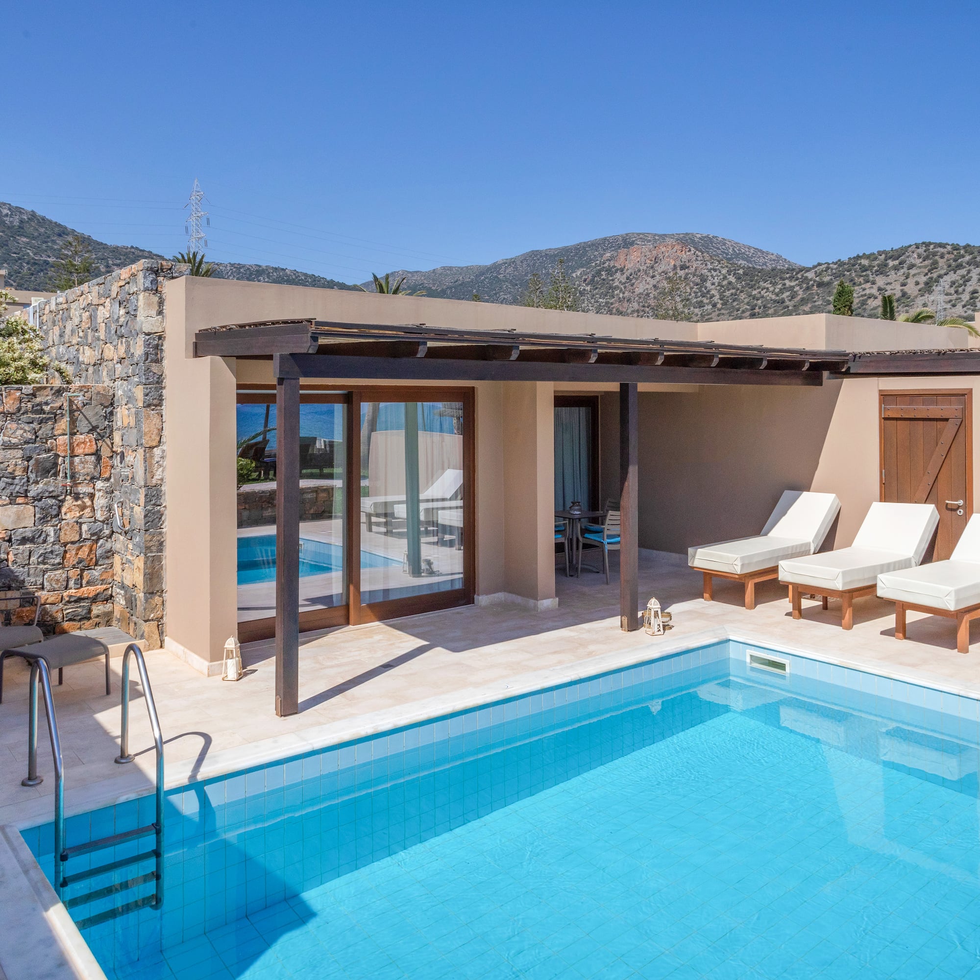 a swimming pool with chairs and a stone wall