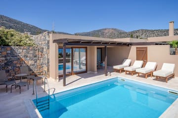 a swimming pool with chairs and a stone wall