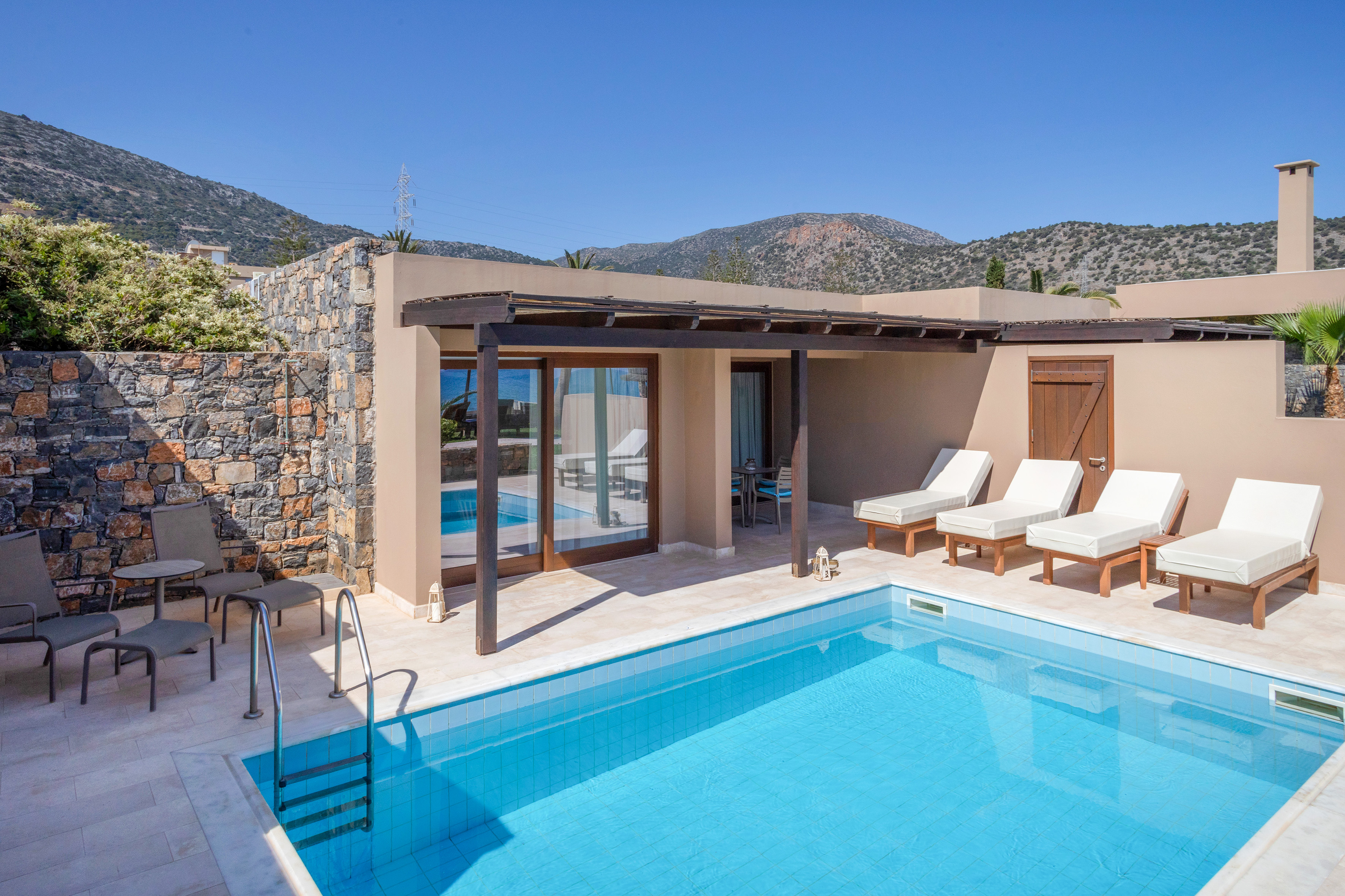 a swimming pool with chairs and a stone wall