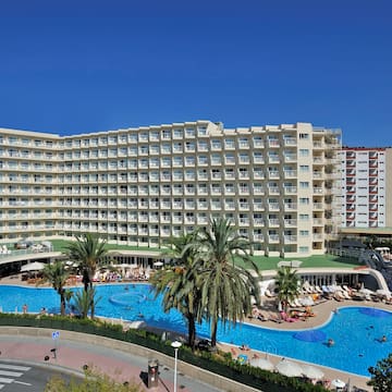a large hotel with swimming pool and palm trees