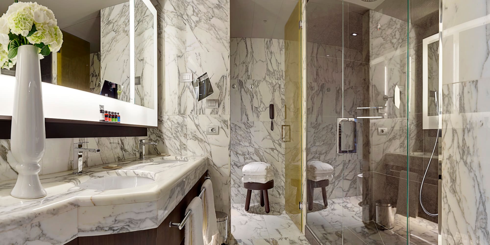 a bathroom with marble walls and a glass shower