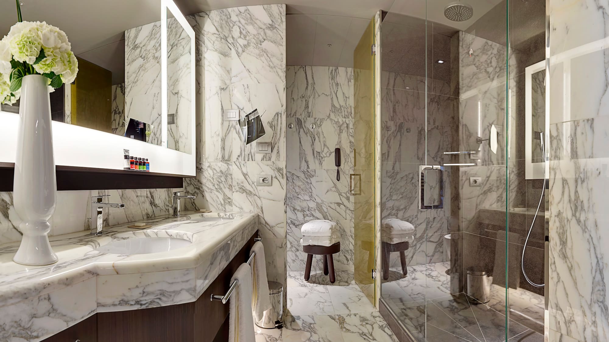 a bathroom with marble walls and a glass shower