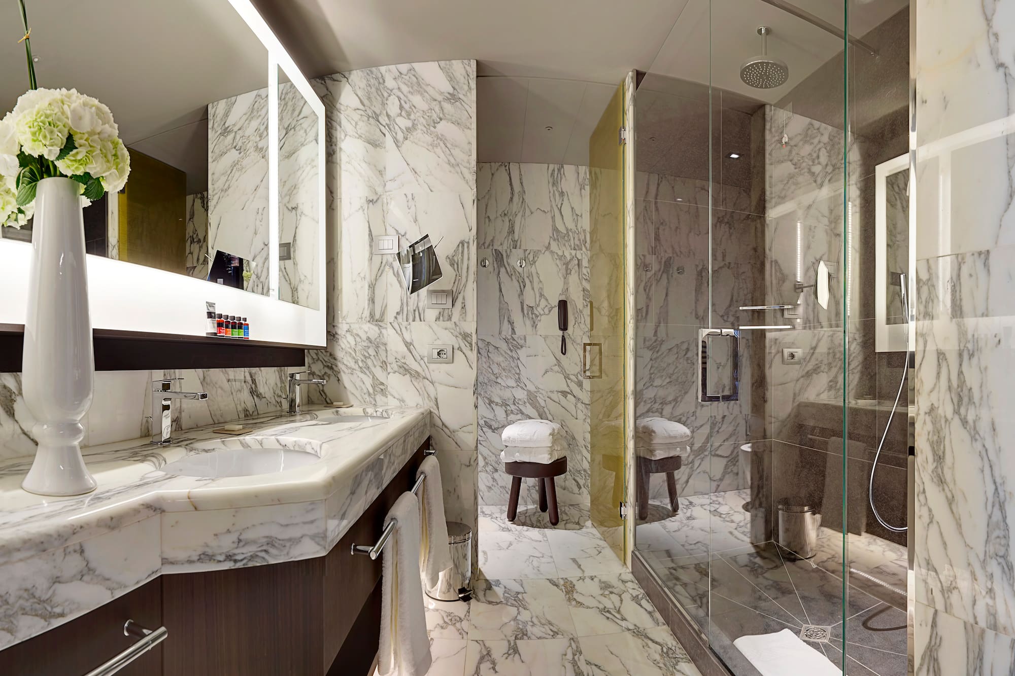 a bathroom with marble walls and a glass shower