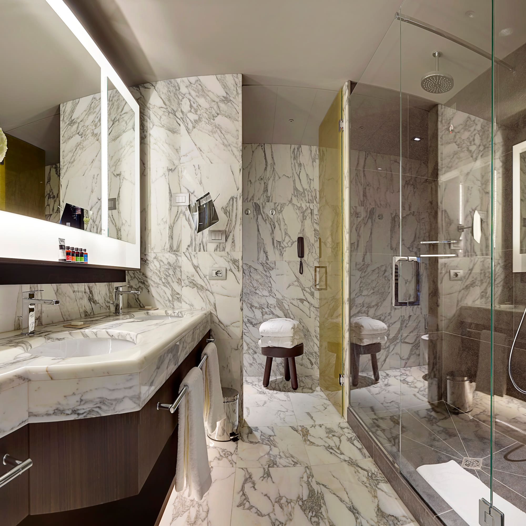 a bathroom with marble walls and a glass shower