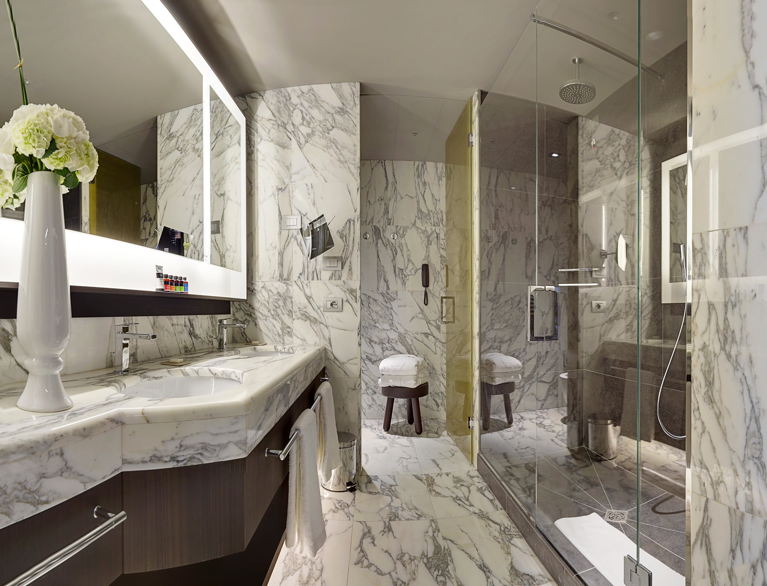 a bathroom with marble walls and a glass shower