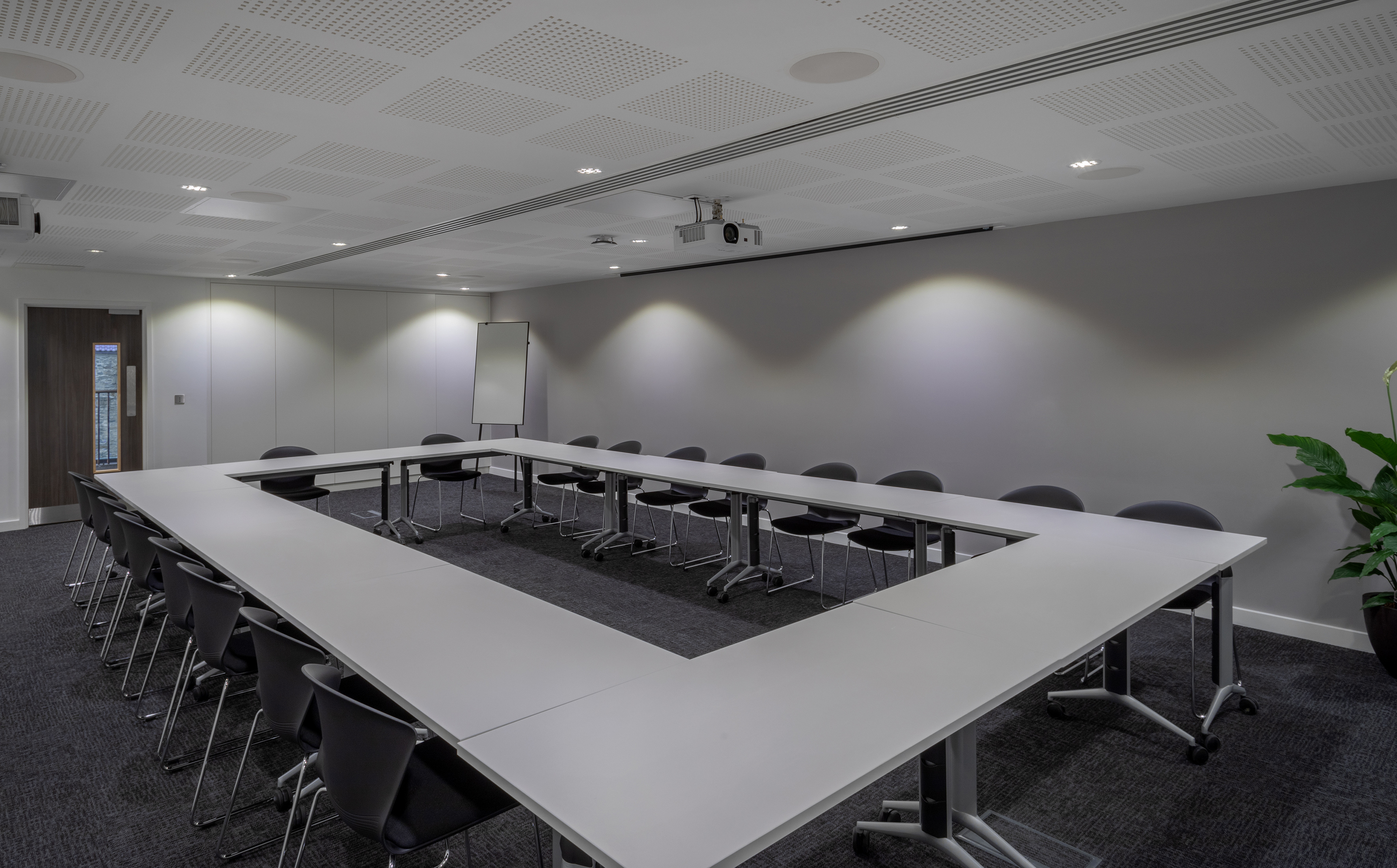 Spacious U-shaped conference room with projector and modern seating.