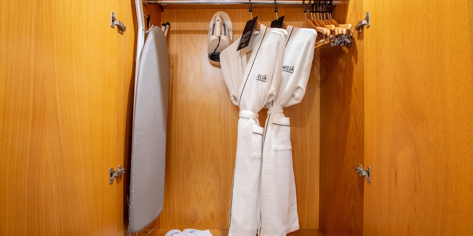 a closet with white bathrobes and slippers
