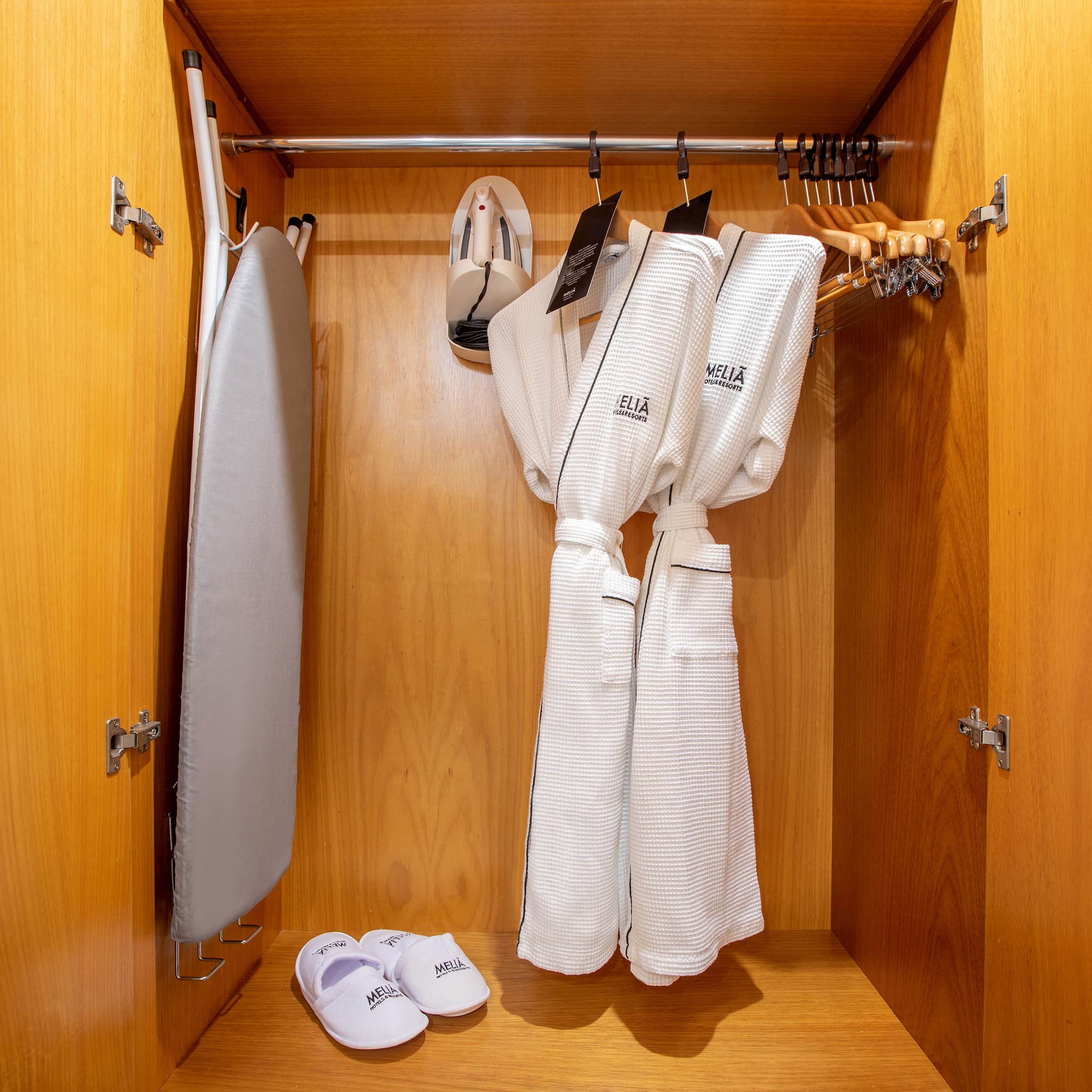a closet with white bathrobes and slippers