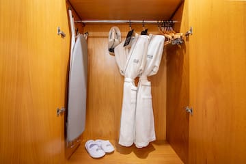 a closet with white bathrobes and slippers