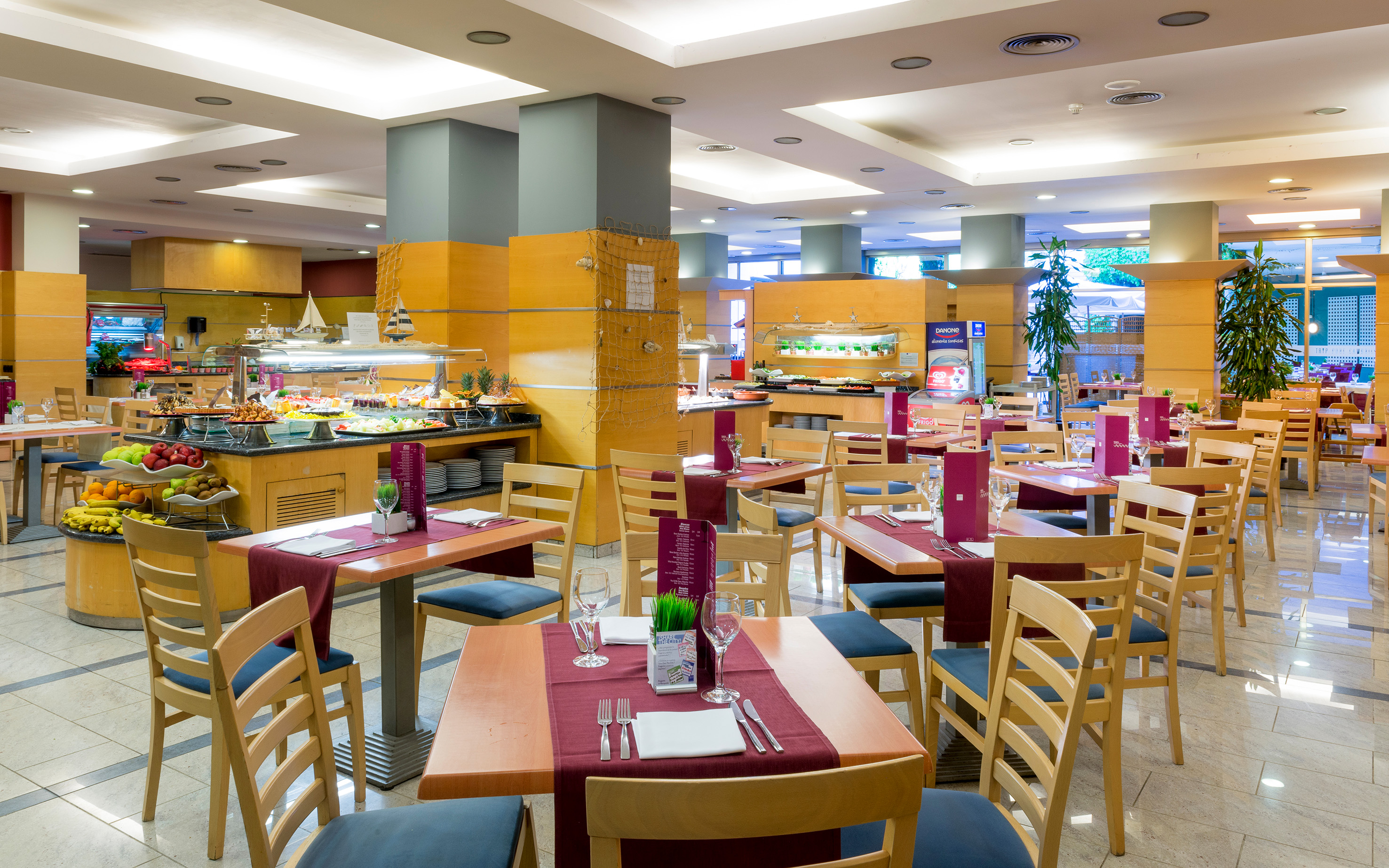 Modern resort buffet restaurant with dining tables and a diverse food spread.
