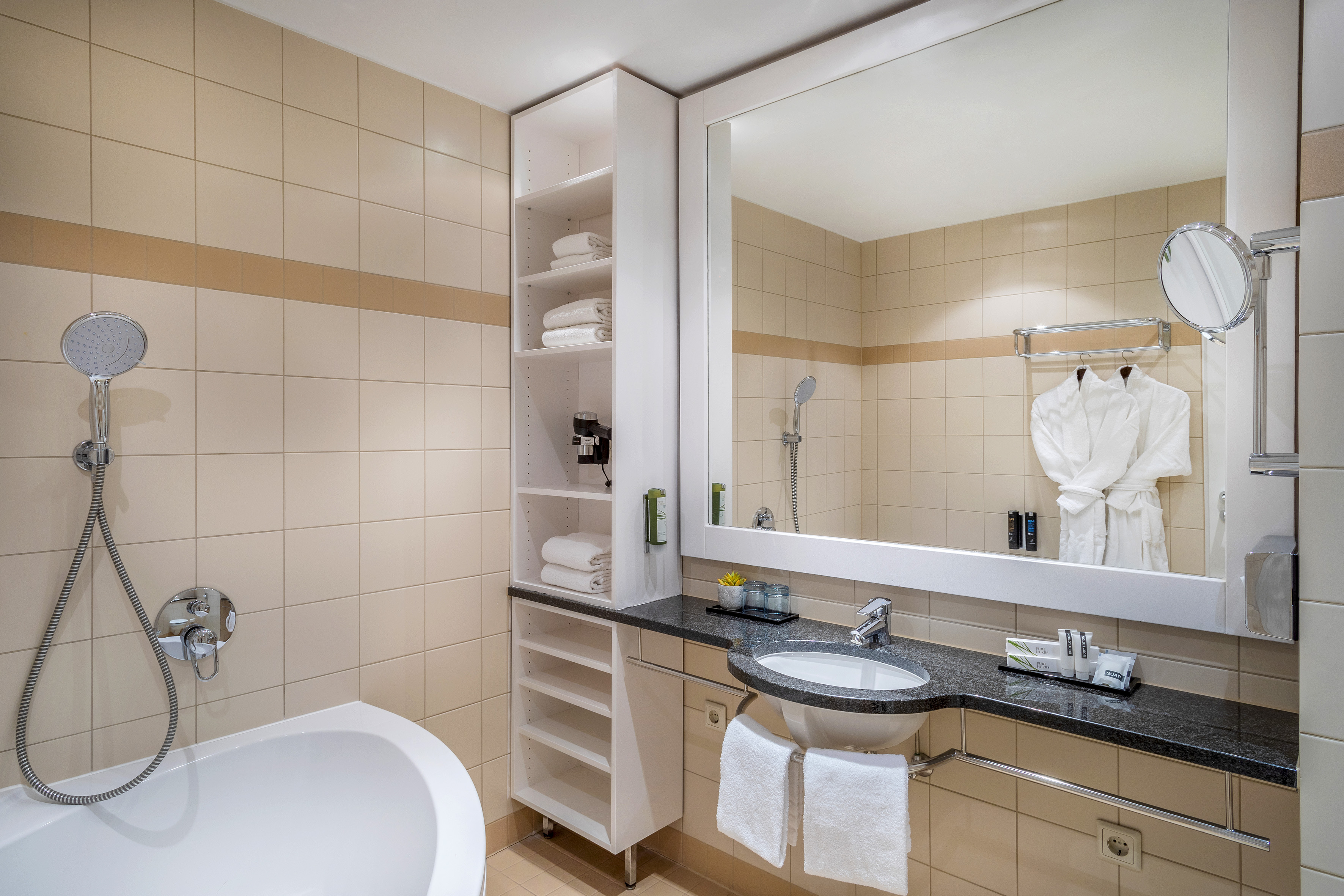 Modern hotel bathroom with bathtub, shower, vanity, mirror, and fresh towels.