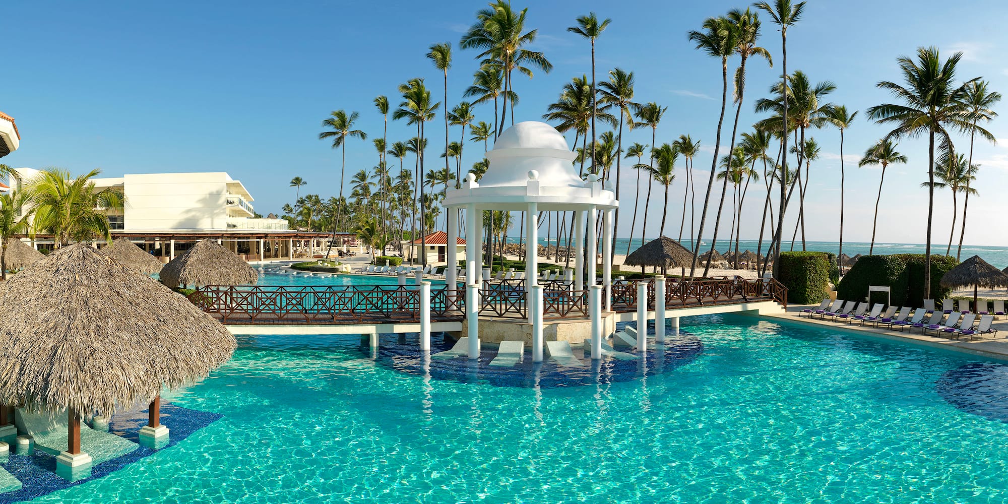 a white gazebo over a pool with palm trees