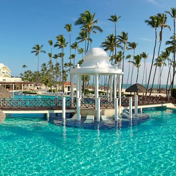 a white gazebo over a pool with palm trees