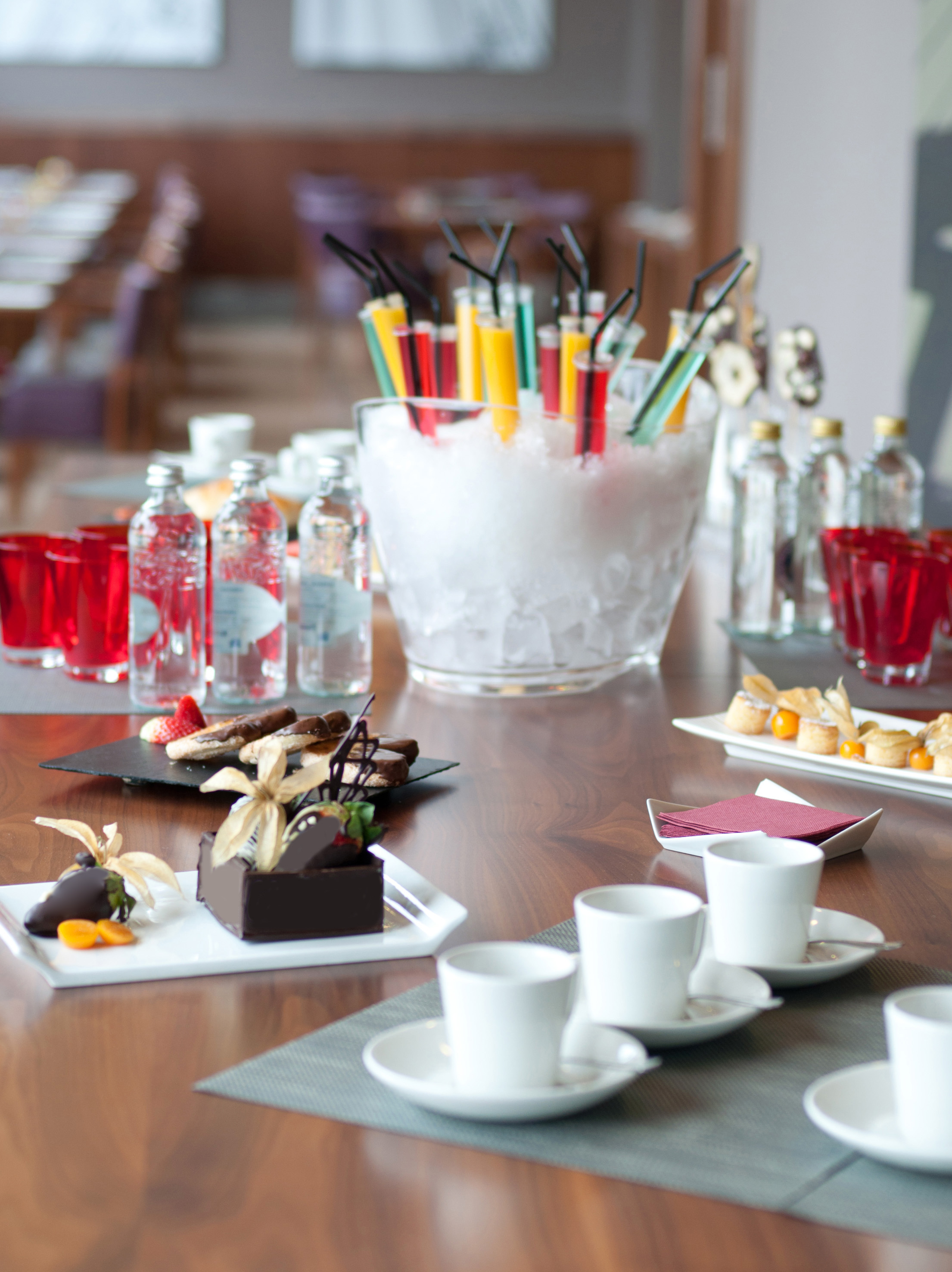Cocktails, chocolate desserts, bottled water, and coffee cups on a refreshments table.