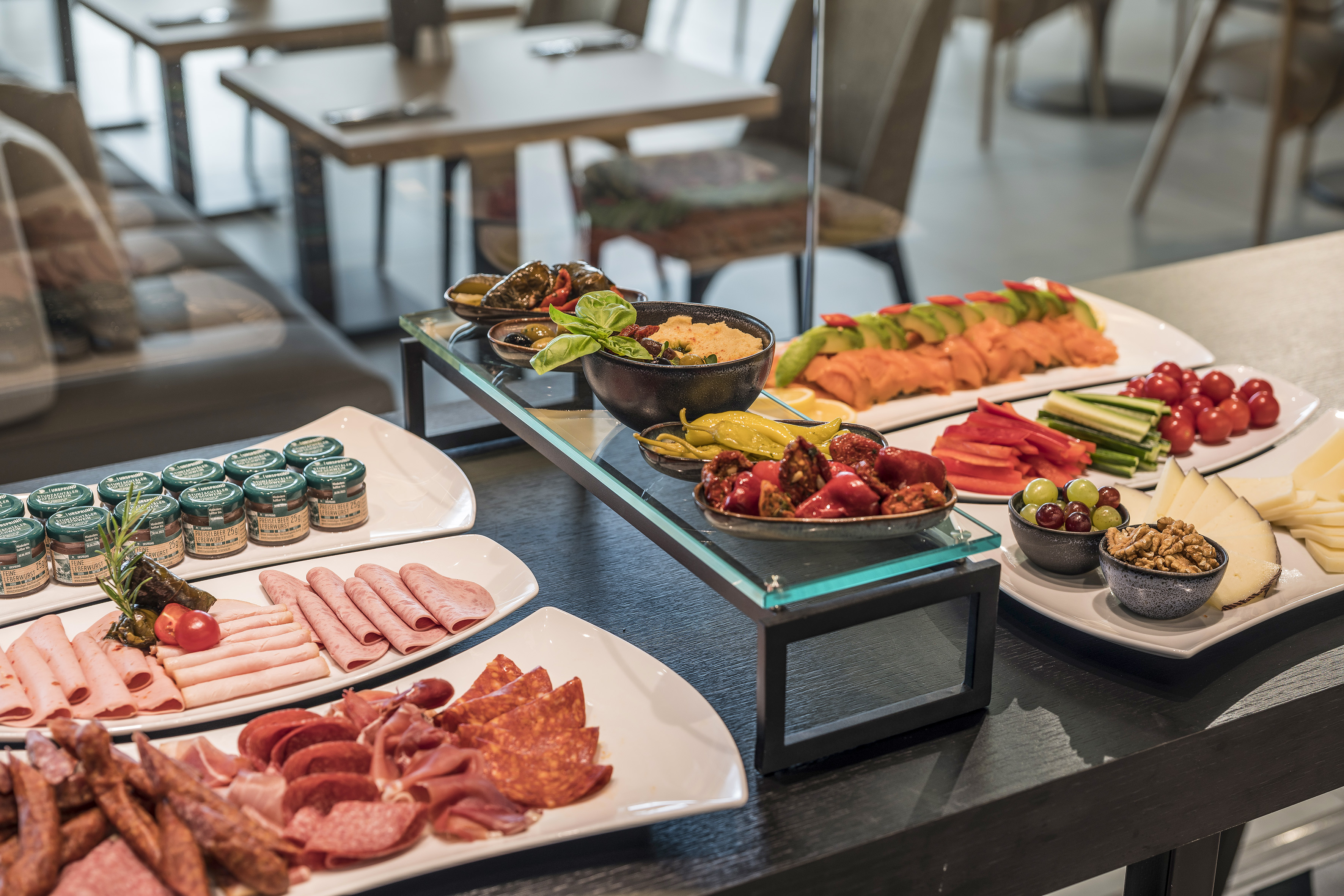 Rich hotel buffet with cold cuts, cheese, smoked salmon, hummus, and fresh produce.